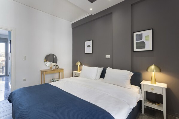 A modern bedroom with a large bed, bedside tables with lamps, and artwork on the walls. - Modern Renovated Apartment in Metaxourgio (Athens)