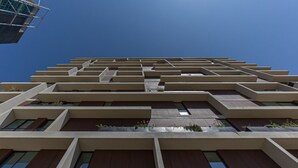 Ein mehrstöckiges Gebäude mit modernem architektonischen Design, das eine Reihe von Balkonen und Fenstern aufweist.