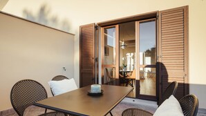 Un espacio de comedor al aire libre con una mesa, sillas y vistas del interior a través de un puerta de cristal.