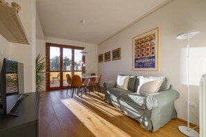 Un salon moderne avec un canapé, une table à manger et des chaises, un téléviseur et une affiche accrochée au mur.