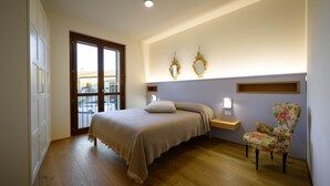 Un dormitorio con cama, una silla, una mesita de noche y un ventanal.