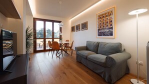 Una sala de estar moderna con un sofá, una mesa de comedor con sillas, un televisor y un cartel en la pared.