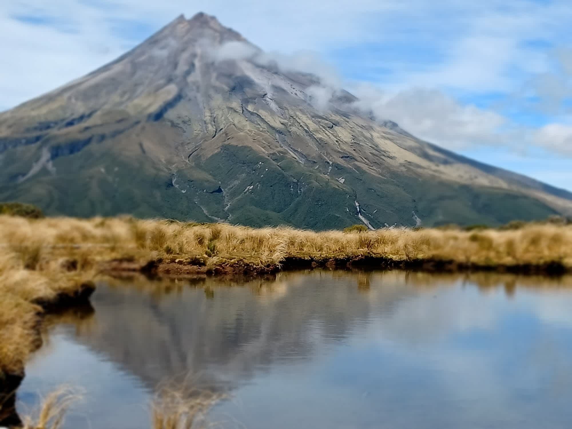 Ein Berg spiegelt sich klar in stillem Wasser.