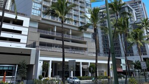 Ein mehrstöckiges Hotel im modernen Stil, mit Balkonen und einem auffälligen 'Hawaiian'-Schild.
