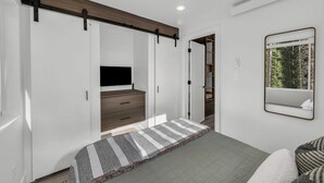A bedroom with a bed, a TV, a wardrobe, and a mirror. - Unwind and Unplug at #5 Tiny Cabin (Brian Head)