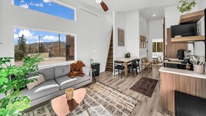 A modern living room with a sofa, coffee table, and a dining area with a table and chairs. - Unwind and Unplug at #5 Tiny Cabin (Brian Head)
