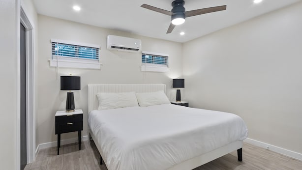 Ein Schlafzimmer mit einem großen Bett, zwei Nachttischen mit Lampen, einer Klimaanlage und einem Deckenventilator.