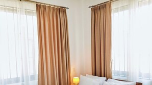 A neatly made bed with white linens, a bedside table with a lamp, and a ceiling fan. - Ridge Estates - Bahari Beach (Dar es Salaam)