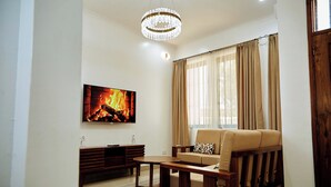 A living room with a flat-screen TV, a wooden coffee table, a beige sofa, and a chandelier. - Ridge Estates - Bahari Beach (Dar es Salaam)