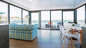 Ein modernes Interieur mit einer Couch, einem Essbereich und großen Fenstern mit Meerblick.