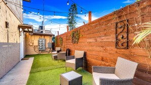 Un jardín trasero con césped artificial, mobiliario de mimbre y una valla de madera.