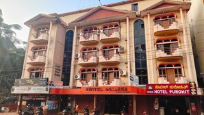 A multi-story building with balconies, a sign for Hotel Gokarna, and a Pure Veg Hotel Purohit sign. - Hotel Gokarna International (Kumta)