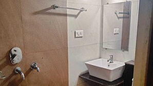 A bathroom with a shower, sink, and toilet. - Hotel Gokarna International (Kumta)