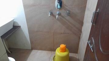 A small bathroom with a toilet, a sink, and a shower area.