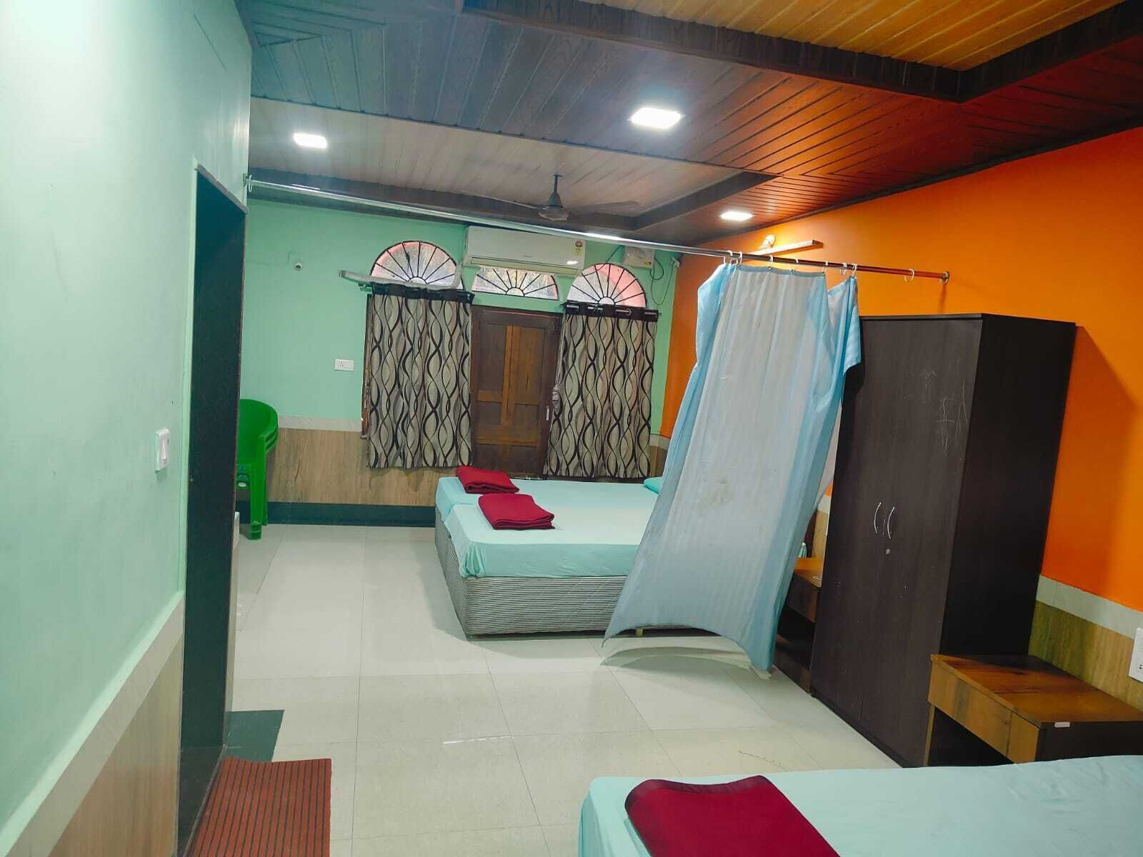 A room with two beds, a wardrobe, and a curtain.