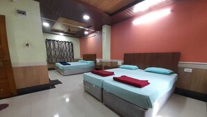 A hotel room with two beds, a large window, and a ceiling fan. - Hotel Gokarna International (Kumta)