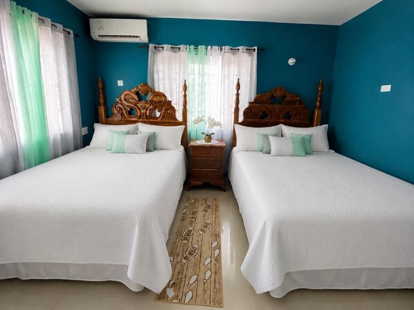 Una camera da letto con due letti, una testiera in legno, un comodino, un vaso con fiori e un tappeto decorato.