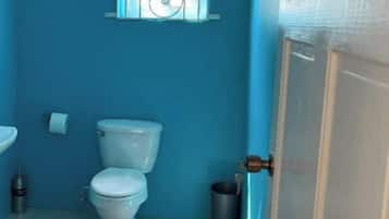 A small bathroom with a toilet, a sink, and a window with decorative bars.