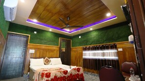 A hotel room with a wooden ceiling, green wall, and a bed with a floral bedspread. - Shree Murlidhar Farm and resort (Mendarda)