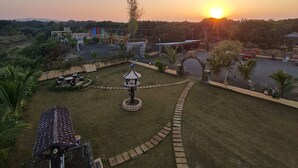 A park with a gazebo, a playground, and a view of the sunset over a body of water. - Shree Murlidhar Farm and resort (Mendarda)