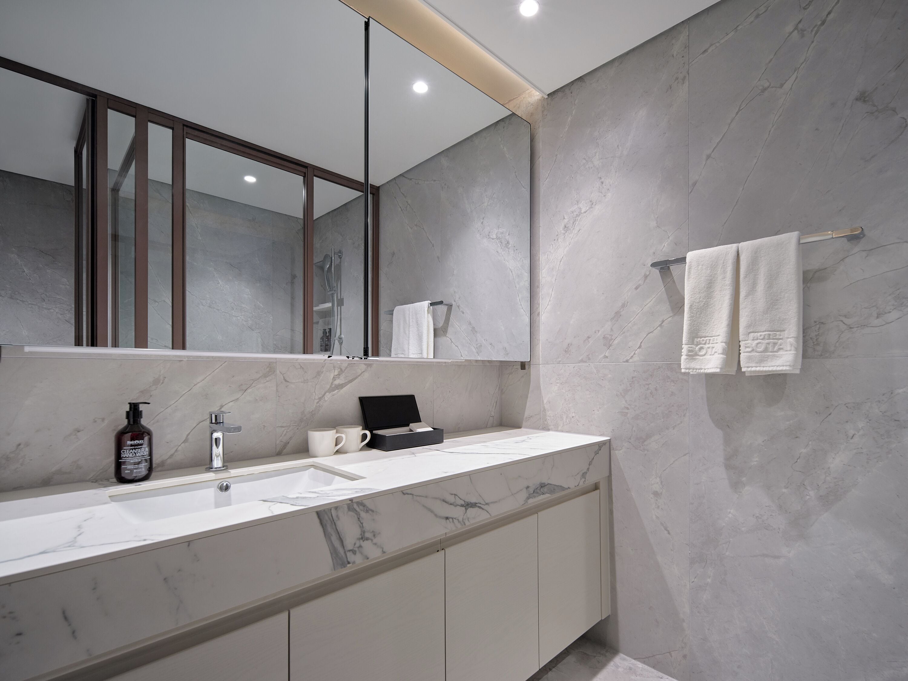 Une salle de bain moderne avec un comptoir en marbre, un grand miroir et un porte-serviettes.
