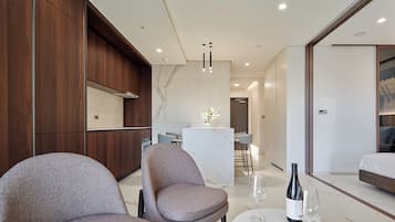 A modern hotel room with a dining area, a sofa, and a table with wine glasses and bottles.