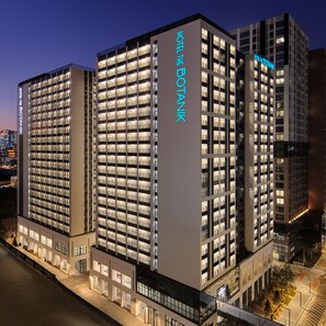 Un moderno edificio de hotel con varios pisos, ventanas amplias y un cartel llamativo que dice "HOTEL THE BOTANK".