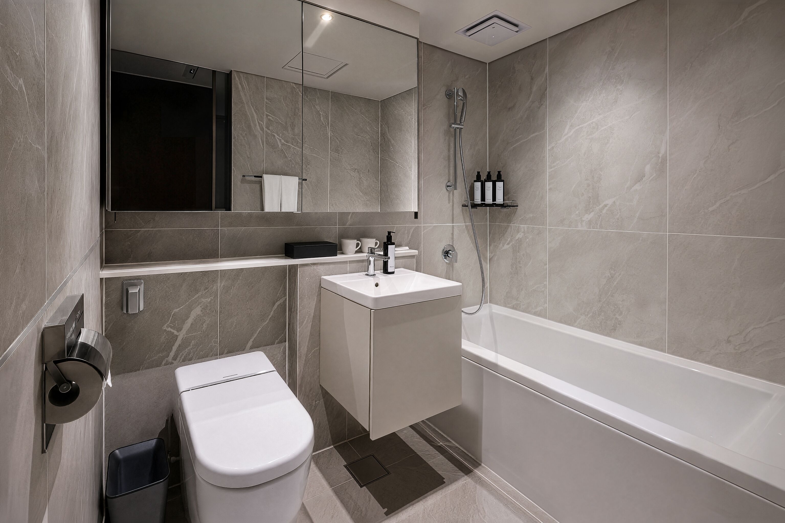 A modern bathroom with a toilet, sink, and bathtub.