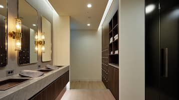 Un baño moderno con tocador de mármol, un espejo grande y un mueble negro con estantes.