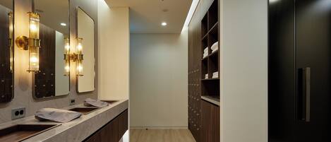 A modern bathroom with a marble vanity, a large mirror, and a black cabinet with shelves.