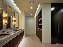 Un baño moderno con tocador de mármol, un espejo grande y un mueble negro con estantes.