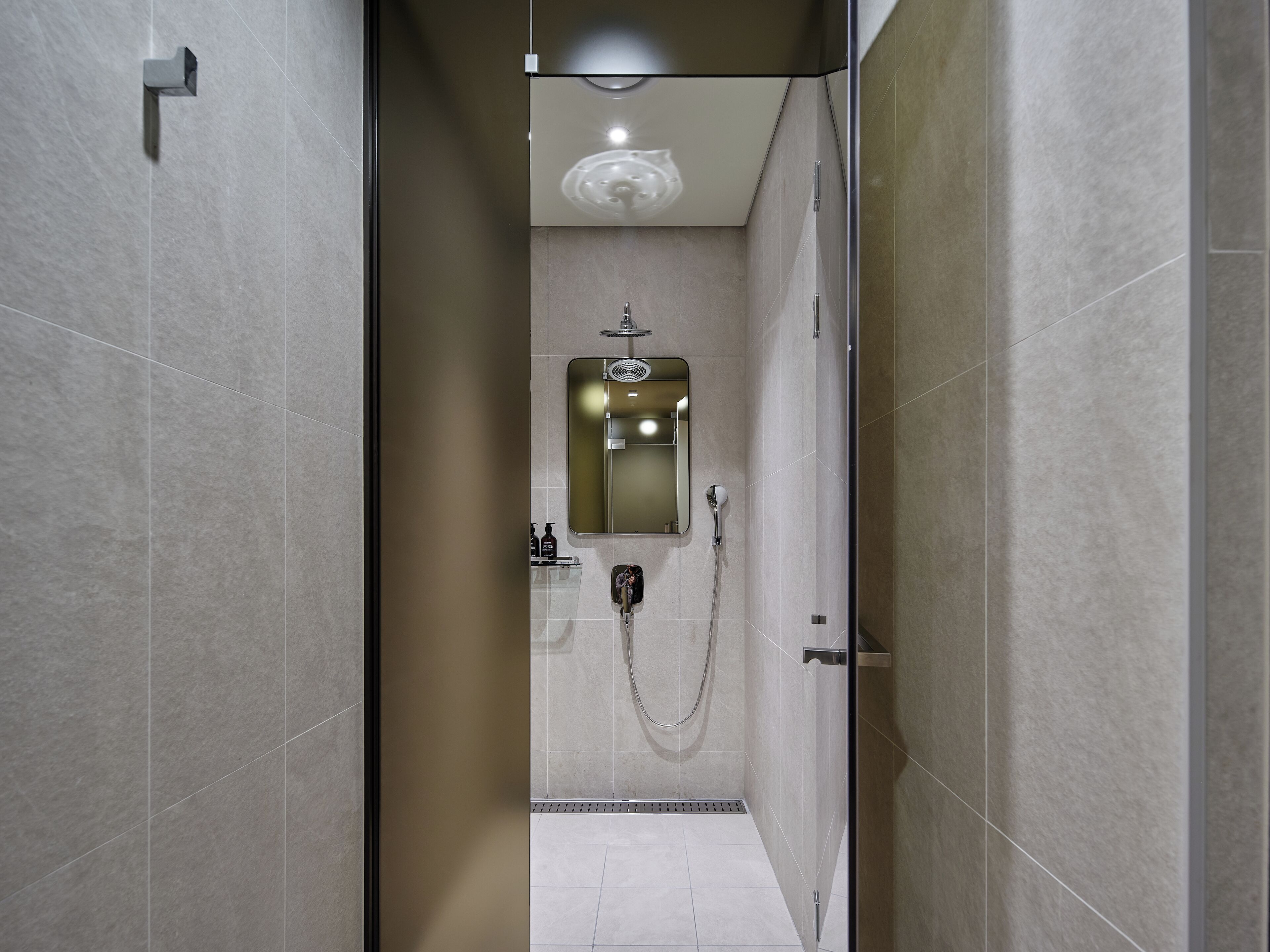 Un bagno moderno con doccia, specchio e illuminazione a soffitto.