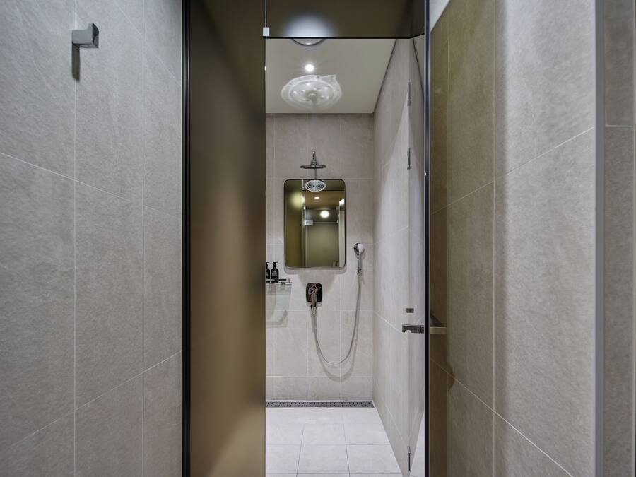 A modern bathroom with a shower, a mirror, and a ceiling light.