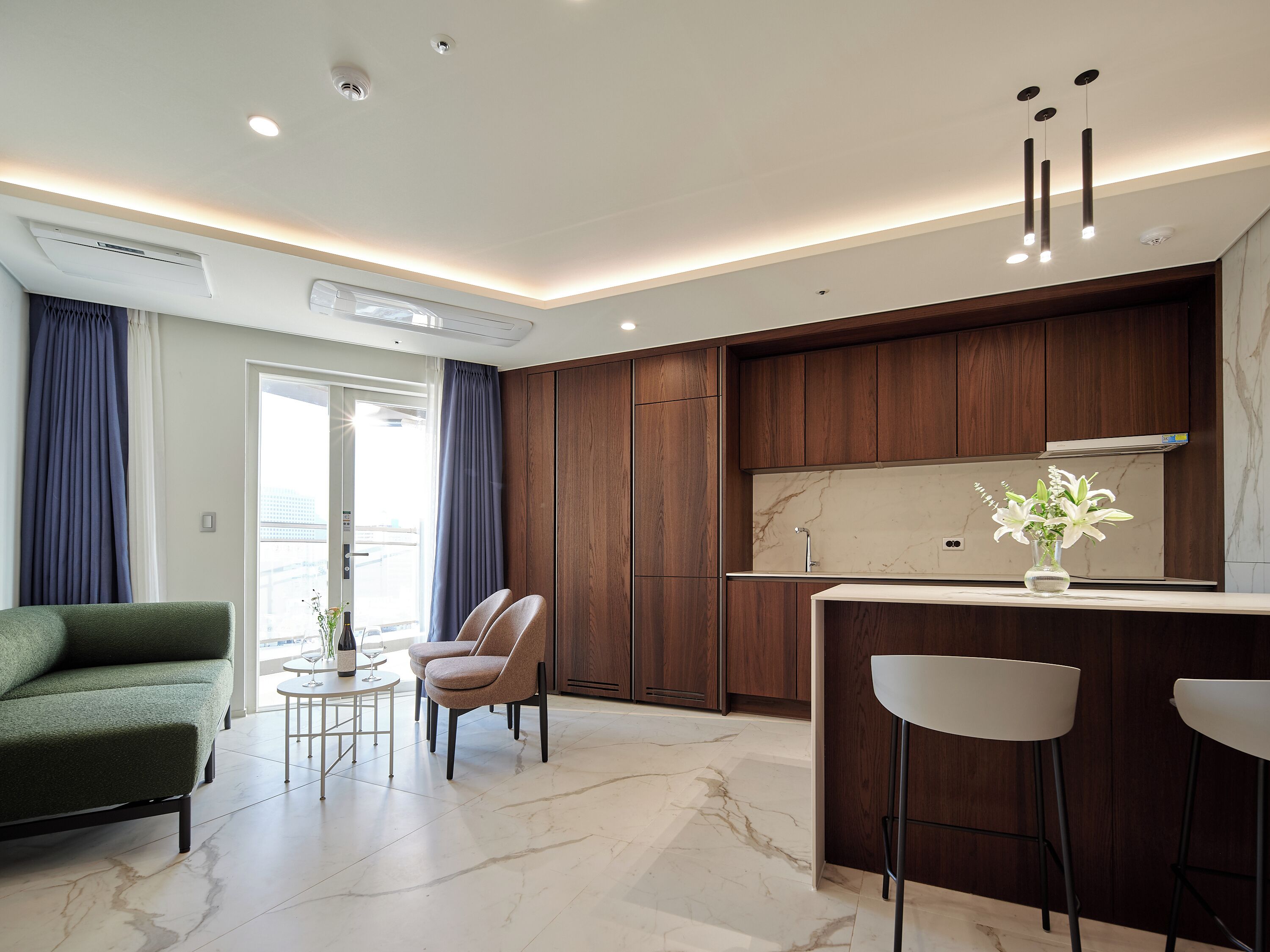 A modern kitchen with wooden cabinets, a marble countertop, and a bar area.