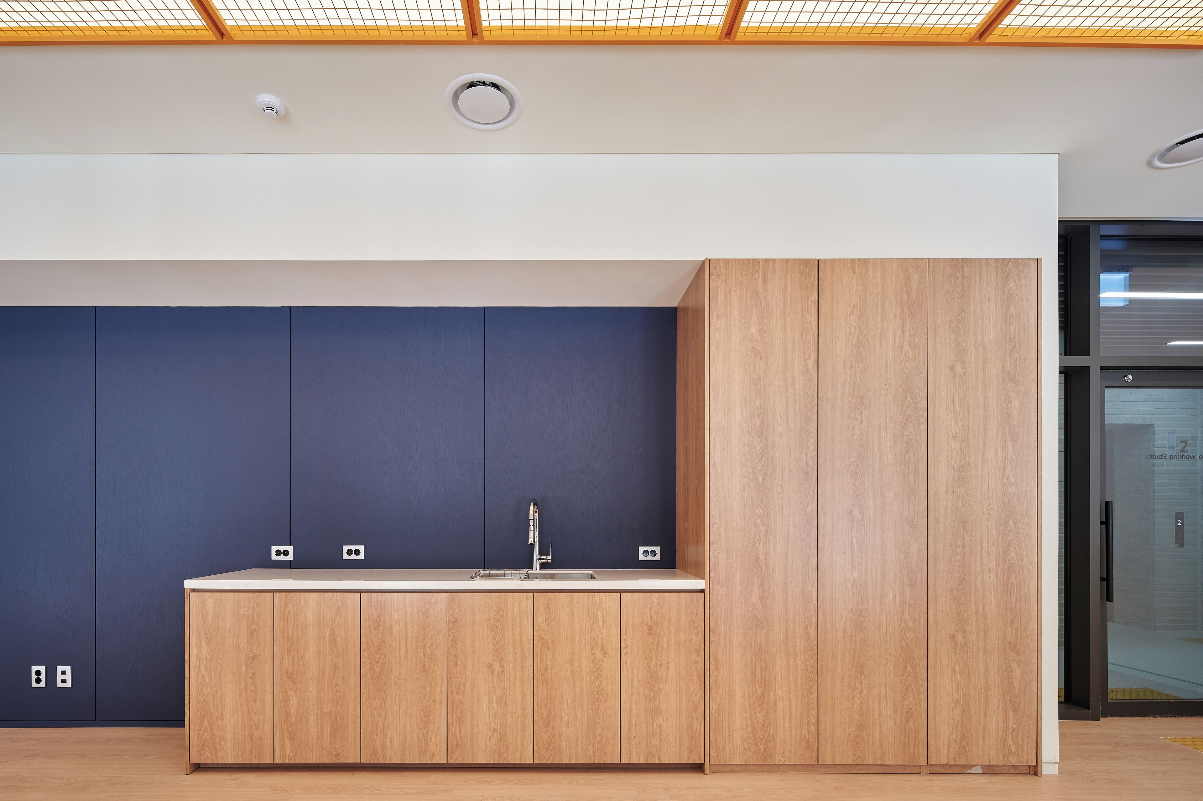 Een moderne keuken met een houten aanrecht, een spoelbak en kasten tegen een blauwe muur.