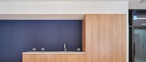 Una cocina moderna con encimera de madera, un lavamanos y armarios frente a una pared azul.