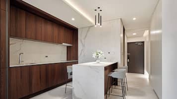 A modern kitchen with wooden cabinets, a marble countertop, and a central island with bar stools.