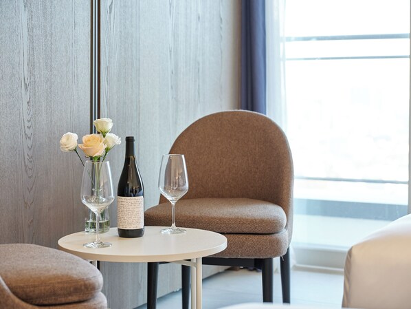 A table with a bottle of wine, a glass, and a vase with flowers in a modern room with a large window. - HOTEL THE BOTANIK SEWOON MYEONGDONG (Seoul)