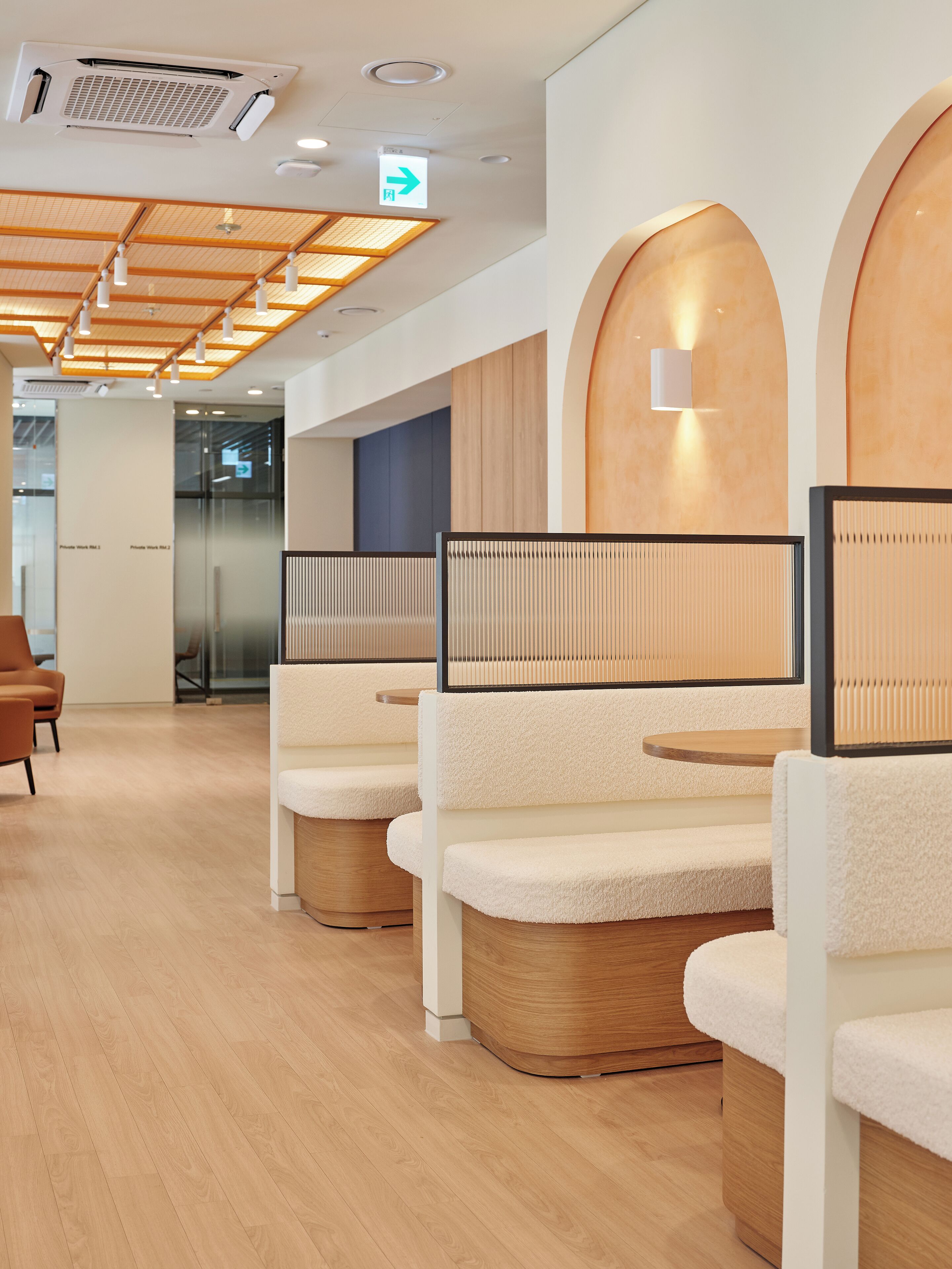 A modern interior with wooden panel ceiling, white cushioned seating, and a glass partition wall.