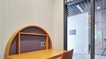 A modern office space with a curved desk, a cushioned chair, and a large window providing a view of the interior.