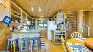 Un interior de madera con una zona de cocina, taburetes de bar y una mesa de comedor.