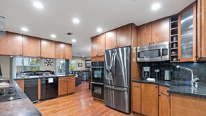 A modern kitchen with wooden cabinets, stainless steel appliances, and a black countertop.