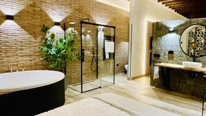 Een moderne badkamer met een groot bad, een glazen douchecabine en een stenen wand.
