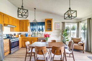 A kitchen with wooden cabinets, a dining table with chairs, a stove, and a chandelier. - Water-View Home w/ Hot Tub in Lake Elsinore! (Lake Elsinore)