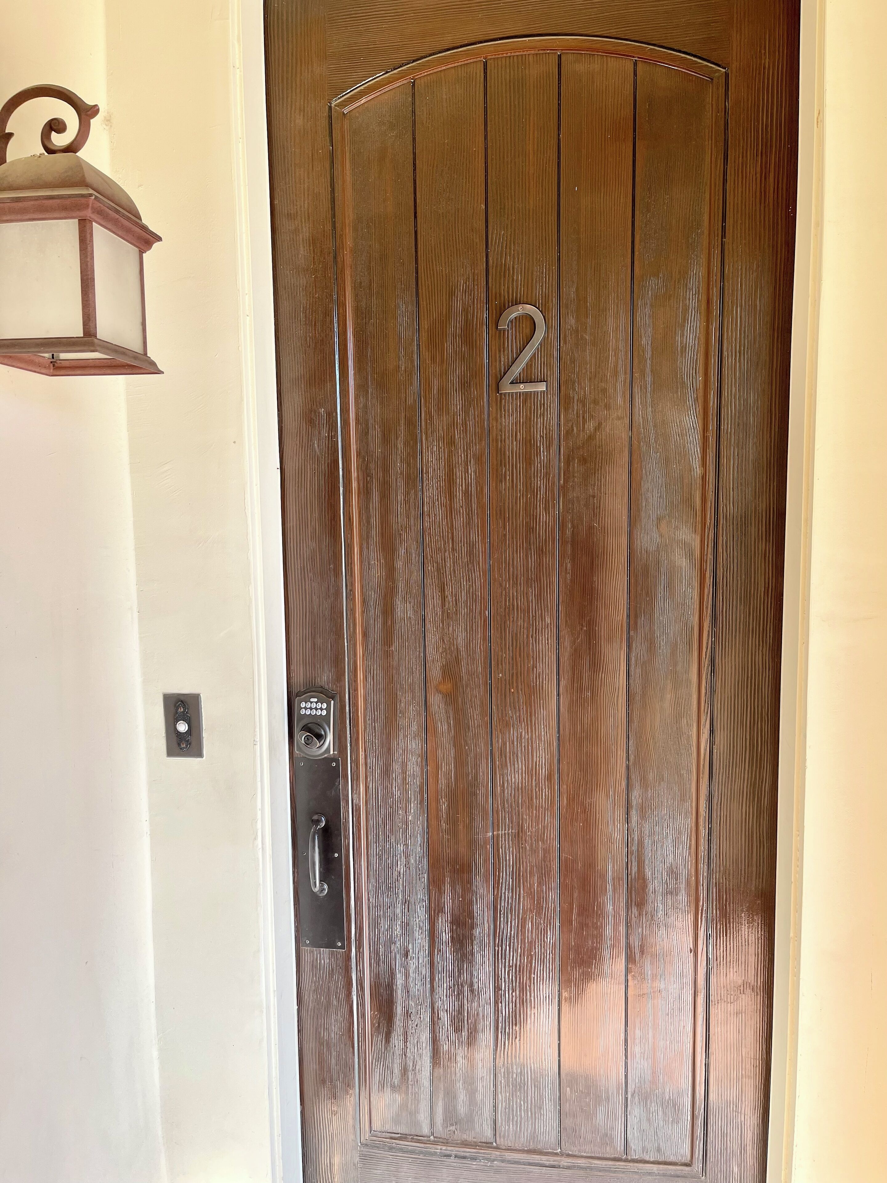 A wooden door with the number 2, a keyhole, and a doorbell.