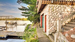 Un edificio in pietra con un pontile in legno che si estende sull'acqua, una scala e vista sull'acqua.