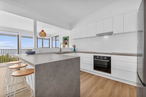 A modern kitchen with a large island, white cabinetry, and a view to the outside.