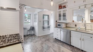 A kitchen with white cabinets, a gas stove, a microwave, and a sink. - Walk to Main Street: Charming Roswell Home! (Roswell)