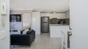 A compact living space with a kitchenette, a sofa, a bed, and a TV. - Sunny 2-Bed in Quiet Location with Balcony (Cannington)