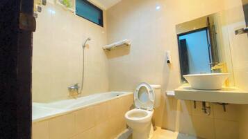 Une salle de bain équipée d’une baignoire, de toilettes, d’un lavabo et d’un miroir.